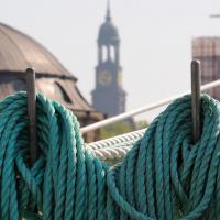 4600_2781 Aufgeschossene Schiffstaue an der Reeling eines Seglers; Turm des Hamburger Michels. | 